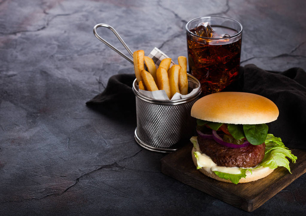 Fresh beef burger with sauce and vegetables and glass of cola soft drink with potato chips fries on stone kitchen background. - Valokuva, kuva