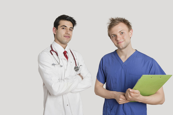 Portrait of doctor standing with coworker over light gray background - Fotoğraf, Görsel
