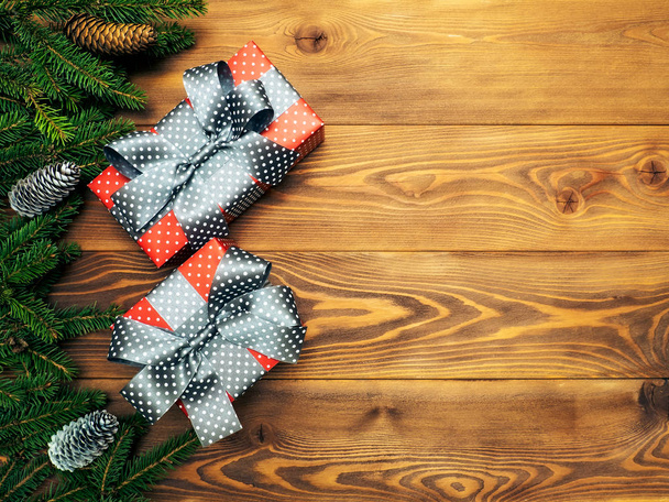 Рождественская композиция Ветки ели с конусами вместе с подарочными коробками на деревянном фоне. Вид сверху. Концепция праздника
 - Фото, изображение