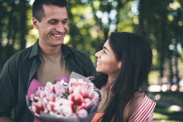 Cute woman turning to her boyfriend after getting flowers from him - Foto, imagen