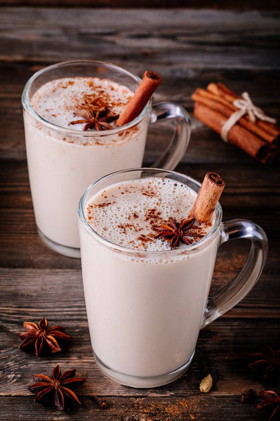 Homemade Chai Tea Latte with anise and cinnamon stick in glass mugs on wooden rustic background - Foto, afbeelding