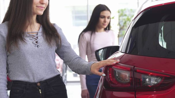 Обрізаний знімок двох жінок, які вибирають автомобілі в дилерському центрі
 - Фото, зображення