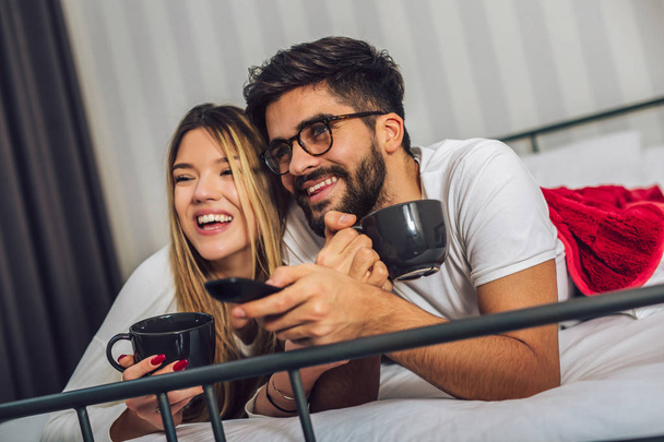Beautiful young couple watching TV in Bed. - Photo, Image