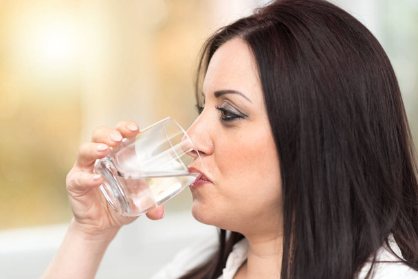 Porträt einer jungen attraktiven Frau, die Wasser trinkt - Foto, Bild