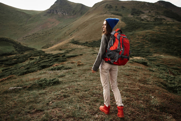 Female traveler wearing stylish clothes while walking on the hill - Photo, image
