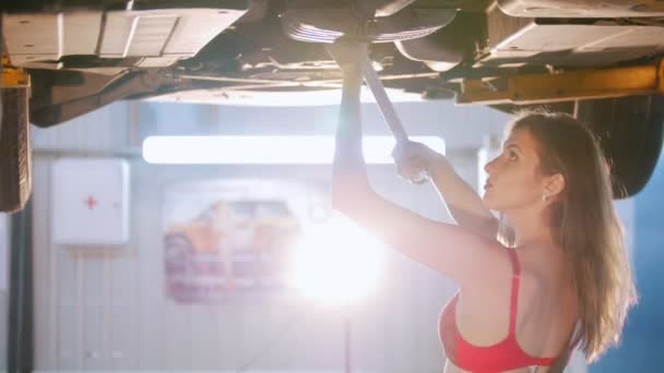 Sexy dziewczyna mechanik pilnie reperuje samochód z klucza - Materiał filmowy, wideo