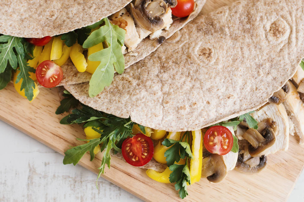 Chicken wrap with mushrooms, cherry tomatoes, bell pepper, parsley and arugula leaves. Balanced meal - Photo, Image