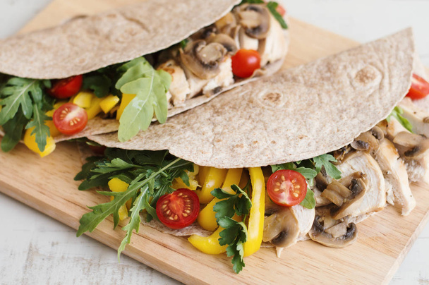 Healthy sandwiches with chicken, mushroom, red cherry tomatoes, yellow bell pepper, parsley and arugula leaves. Healthy whole wheat wrap with protein and vegetables - Foto, Bild