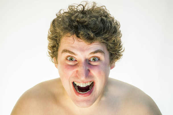 Ördögi dühös sikoltozó göndör fiatalember fehér háttér portréja. - Fotó, kép