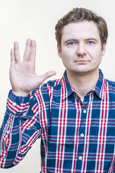 Πορτρέτο του νέους Καυκάσιος εθνότητα μπλε-eyed νεαρός άνδρας δείχνει Vulcan Salute χέρι σύμβολο σε άσπρο φόντο - Φωτογραφία, εικόνα
