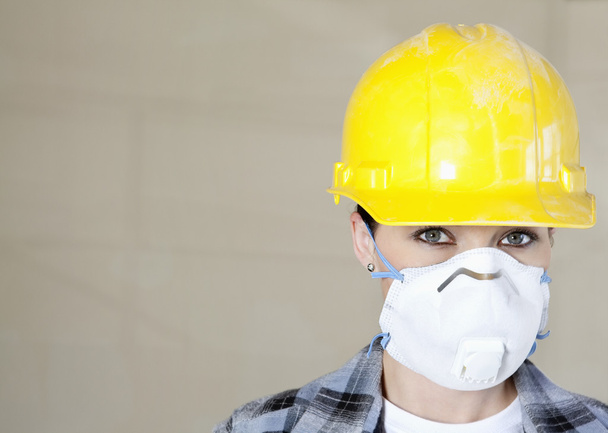 色付きの背景上防塵マスクとヘルメット身に着けている女性の労働者の肖像画 - 写真・画像