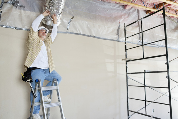Architect on ladder working on ceiling - Foto, Imagen