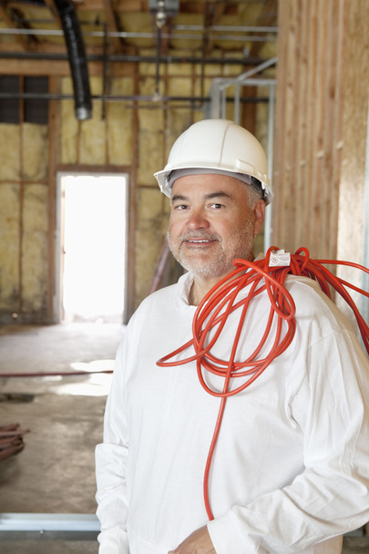 Retrato de um trabalhador da construção civil com um fio elétrico vermelho
 - Foto, Imagem