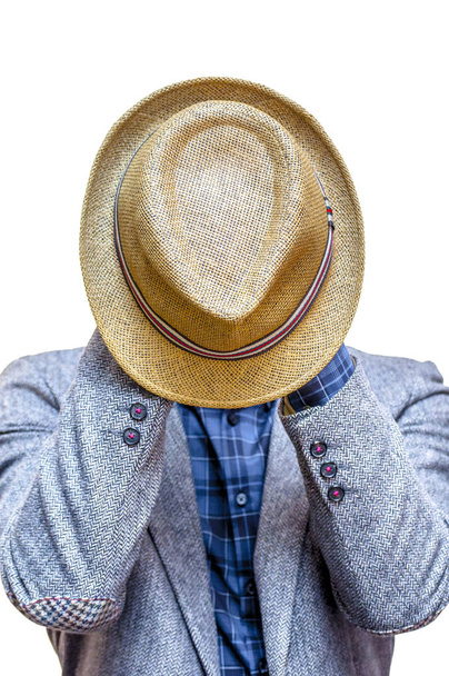 Retrato de hombre desconocido con chaqueta gris y camisa azul que cubre su cara con sombrero de verano aislado sobre fondo blanco
. - Foto, Imagen