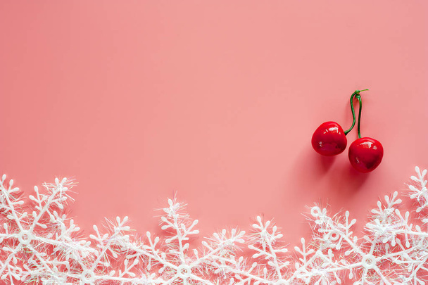Fake Red Cherry mit Weihnachts-Schneeflockenschmuck und Dekoration auf rosa Hintergrund für Weihnachten und Feiertage Konzept - Foto, Bild