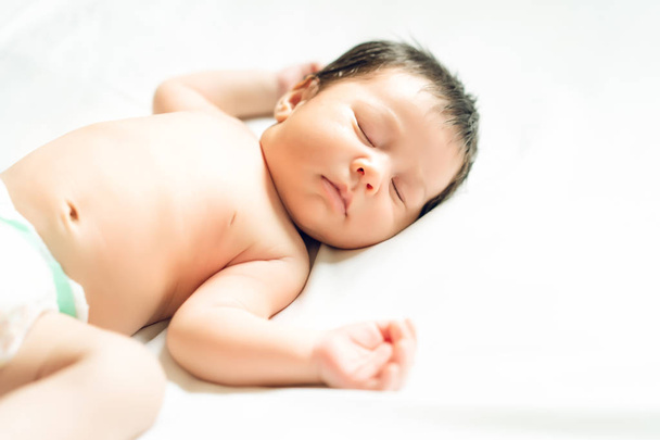 白いベッドの上の新生の赤ん坊が眠っています。家族、新しい生活、子供の頃、初めの概念. - 写真・画像