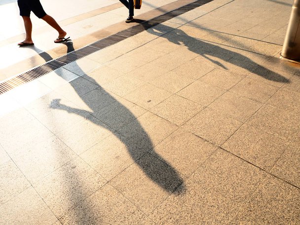 Η σκιά των ανθρώπων στο πεζοδρόμιο. Σκιές των ανθρώπων σε μια πόλη κατά το ηλιοβασίλεμα. - Φωτογραφία, εικόνα