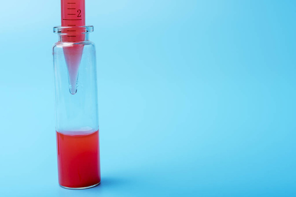 Medizinische Geräte. Bluttestpipette, die einem von mehreren Reagenzgläsern Flüssigkeit zufügt. auf blauem Hintergrund. - Foto, Bild