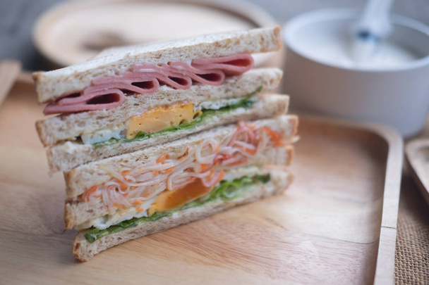 Heerlijke salade, ham en ei sandwich op houten dienblad - Foto, afbeelding