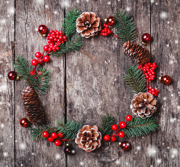 Corona de Navidad de ramas de abeto, conos, decoraciones rojas sobre fondo de madera oscura. Navidad y Feliz Año Nuevo composición. Piso tendido, vista superior
 - Foto, Imagen