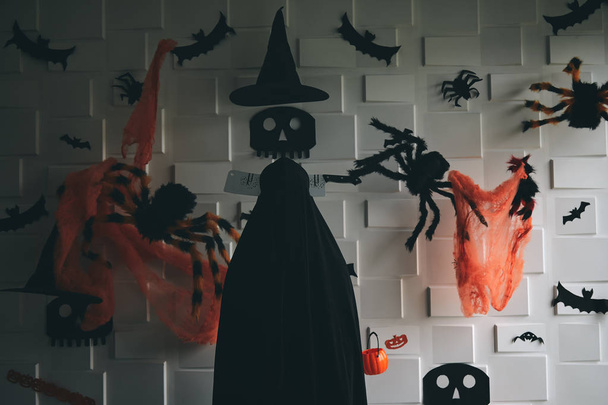 Halloween Concept - Dead zombie with chopper on head standing in the dark tone room with decorated items such as skull, spider, bat and pumpkin - Фото, зображення