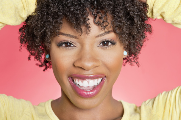 Close-up portrait of an African American woman smiling over colored background - Fotografie, Obrázek