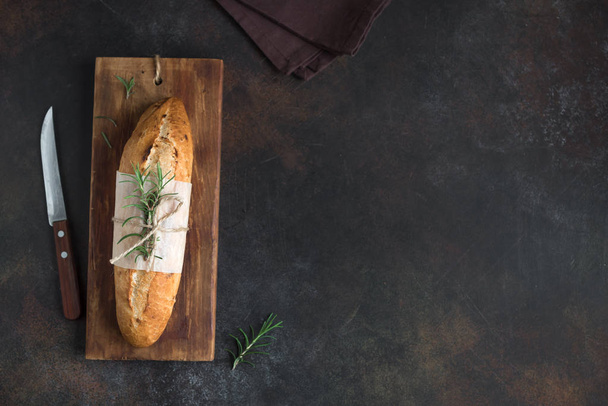 Fresh homemade bread with rosemary on rustic wooden background, top view, copy space. Sourdough mini baguette bread. - Foto, imagen