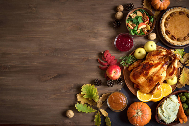Thanksgiving dinner background with turkey and all sides traditional dishes, pumpkin pie, fall leaves and seasonal autumnal decor, top view, copy space. - Zdjęcie, obraz