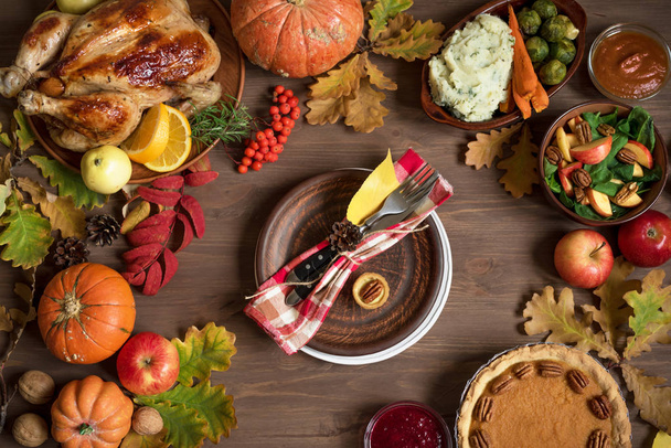 Thanksgiving dinner background with turkey and all sides dishes, pumpkin pie, fall leaves and seasonal autumnal decor around plate table setting, top view. - Zdjęcie, obraz