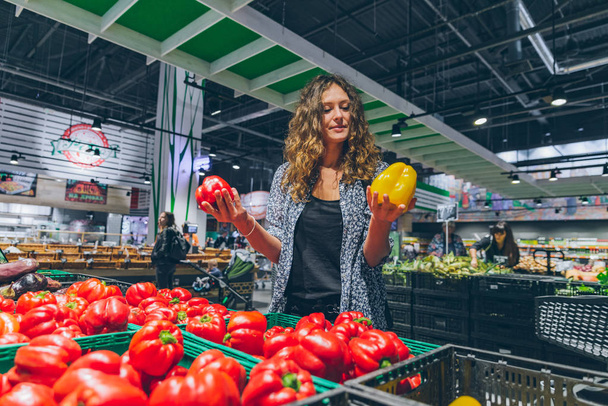 young pretty woman choosing salad paper in grocery store. copy space - Photo, Image