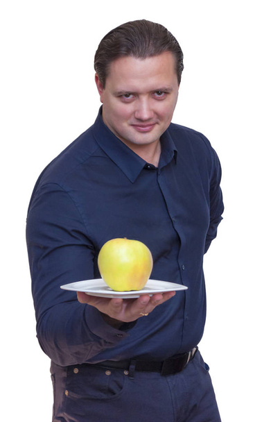 Retrato de hombre joven atlético elegante con camisa azul sostiene una manzana grande en plato blanco
. - Foto, imagen