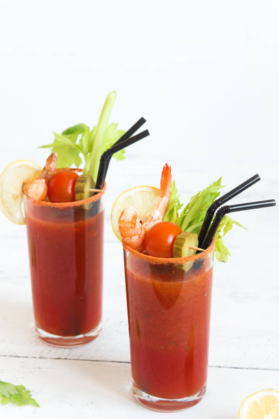 Bloody Mary Cocktail in glasses with garnishes. Tomato Bloody Mary spicy drink on white background with copy space. - Foto, immagini