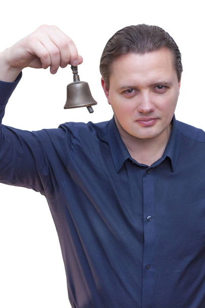 Retrato del joven hombre de etnia caucásica con camisa azul tocando una pequeña campana, pidiendo servicio sobre fondo blanco
. - Foto, Imagen