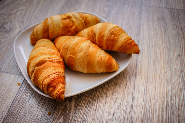 A rich variety of food photography Croissant.Delicious croissants on a square white plate on a wooden tabletop. - Fotó, kép