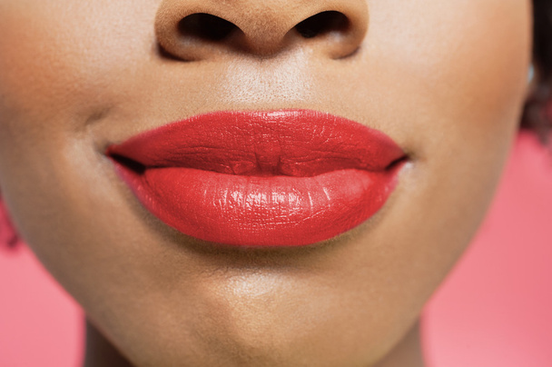 Close-up view of an African American woman's red lips over colored background - Foto, afbeelding