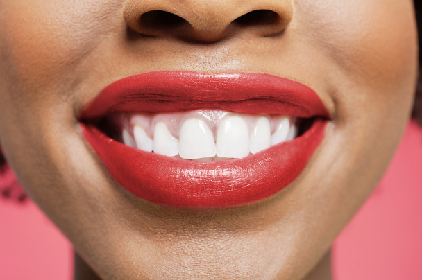 Close-up detail of an African American woman smiling over colored background - Valokuva, kuva