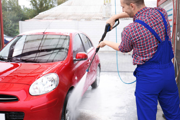 Male worker cleaning vehicle with high pressure water jet at car wash - Фото, зображення