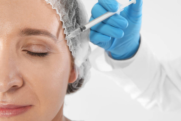 Woman getting facial injection on white background, closeup. Cosmetic surgery concept - Фото, зображення