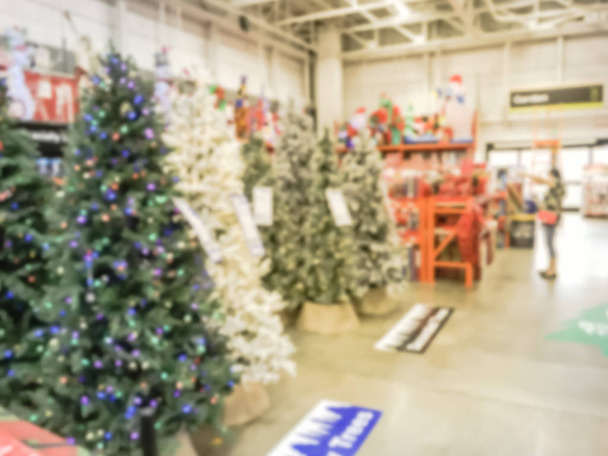 Motie wazig klant winkelen voor kunstmatige kerstboom Multi-Color lichten bij ijzerhandel in Texas, Usa. Intreepupil klassiek, versierd Xmas kleur veranderende kransen, tekenreeksen bokeh ornamenten - Foto, afbeelding