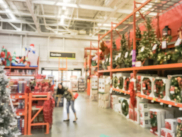 Motie wazig klant winkelen voor kunstmatige kerstboom Multi-Color lichten bij ijzerhandel in Texas, Usa. Intreepupil klassiek, versierd Xmas kleur veranderende kransen, tekenreeksen bokeh ornamenten - Foto, afbeelding