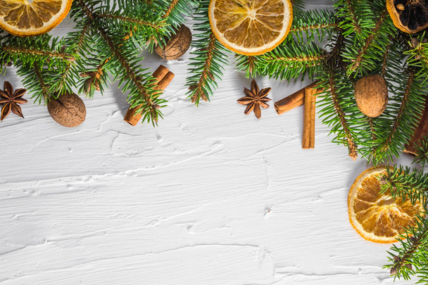 Fond blanc de Noël avec des brindilles fraîches de conifères et d'agrumes secs et place pour le texte
 - Photo, image