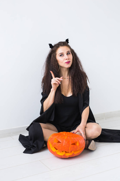 Mujer gótica linda en ropa de estilo halloween con calabaza en las manos
 - Foto, imagen