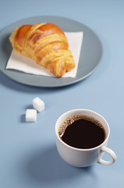 Xícara de café e croissant em prato cinza na mesa azul. Tema do café da manhã ou pausa
 - Foto, Imagem
