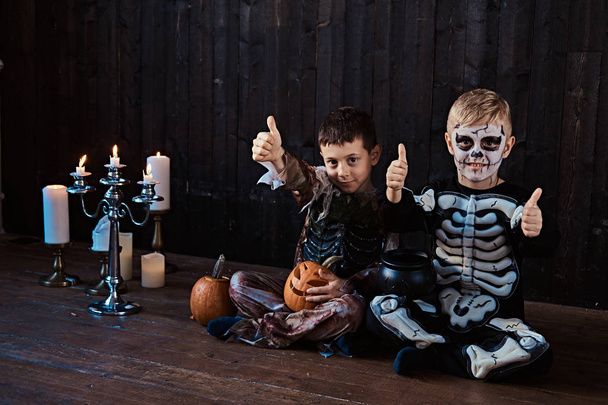 Portrait of two cool schoolboys in scary costumes during Halloween party in an old house. - Photo, Image