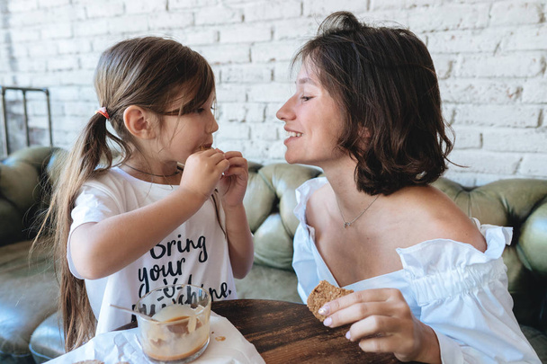 girl with her mother eats oatmeal cookies and have fun - Photo, Image