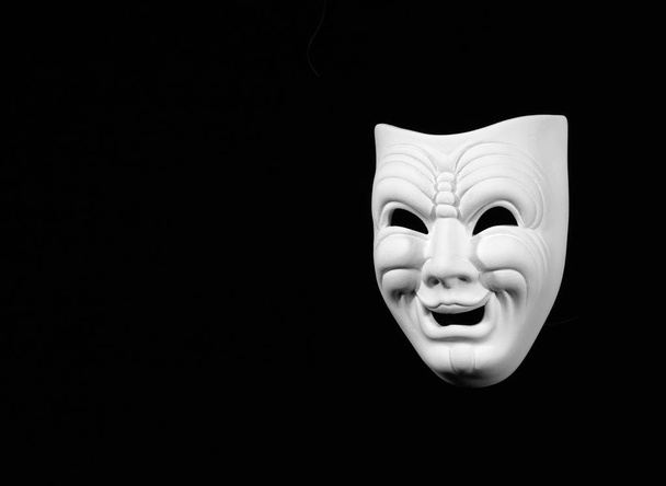 Theatermaske zum Ausdruck der Komödie, weiße Maske auf schwarzem Hintergrund mit freier Textfläche - Foto, Bild