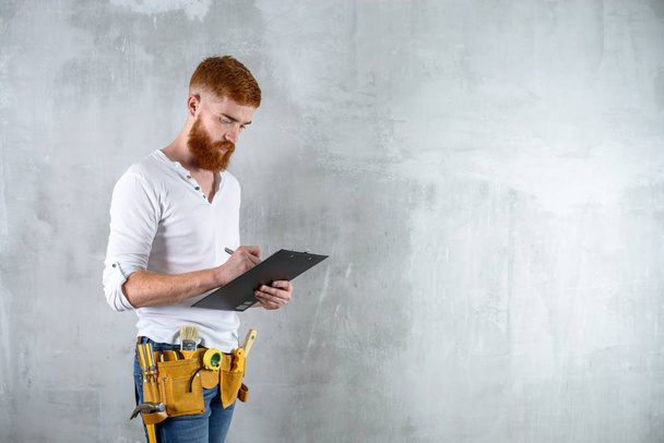 bearded brutal architect, an engineer writes in a tablet - Foto, afbeelding