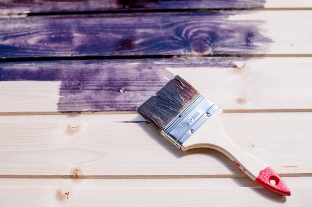 Μισό βαμμένη ξύλινη επιφάνεια. Βαθύ μαύρο χρώμα. Λουστράρισμα φυσικό ξύλο με ξύλινο surface.repair χρώμα brush.paint και την αποκατάσταση του δαπέδου. Αντιγράψτε το χώρο. Βερνίκι πινελιές σε ένα ξύλινο τοίχο - Φωτογραφία, εικόνα