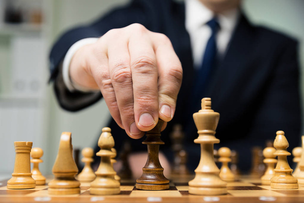 hand of businessman moving chess figure in competition success play. strategy, management or leadership concept - Photo, Image