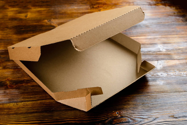Empty craft cardboard pizza box on wooden table - Foto, imagen